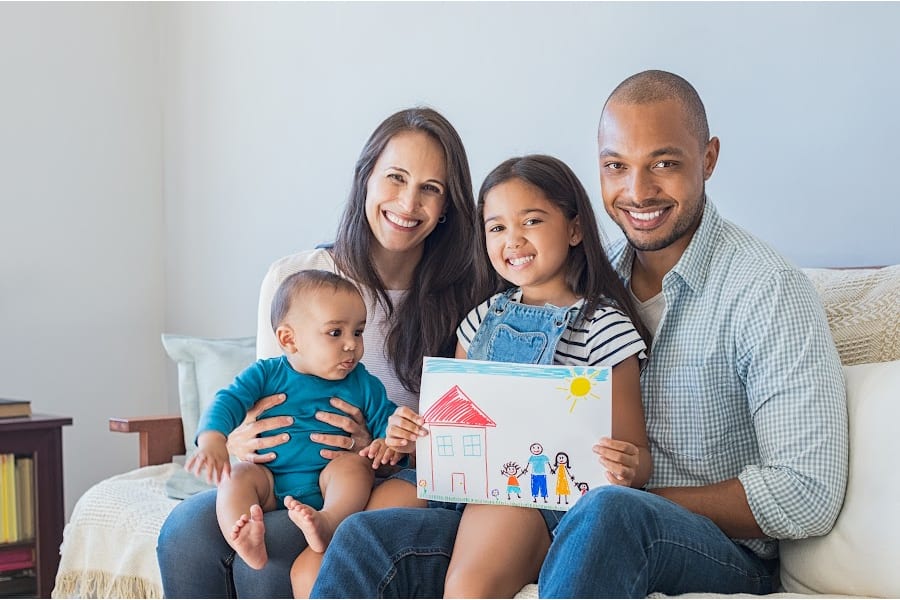 a family with mixed kids sitting on a couch smiling