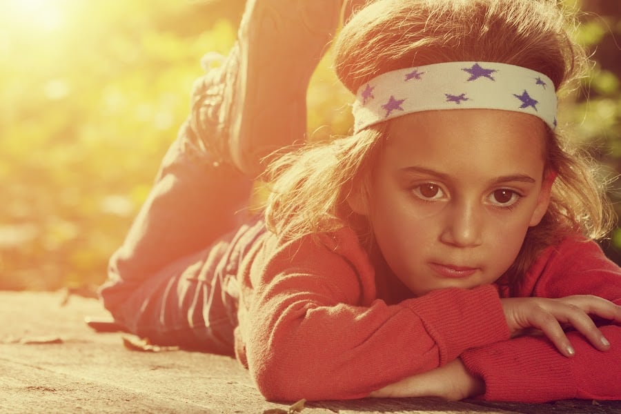young boy laying on the ground looking bored