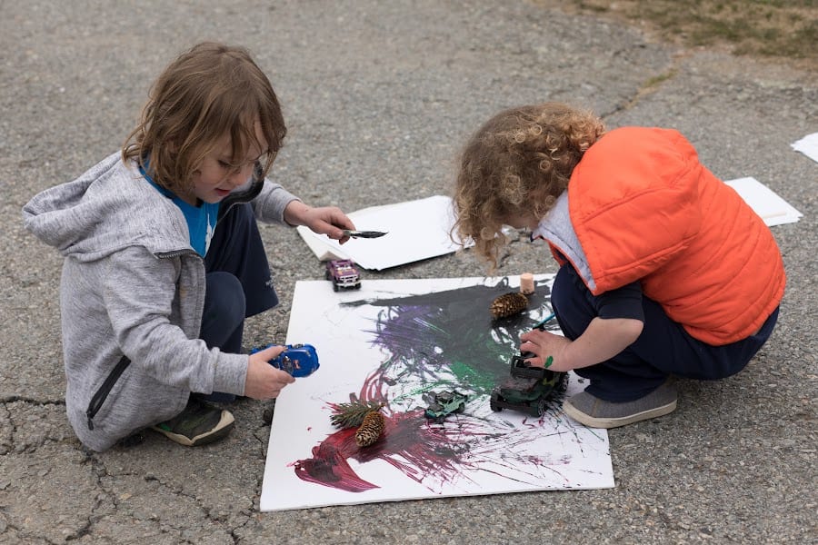 two young children painting with cars outside